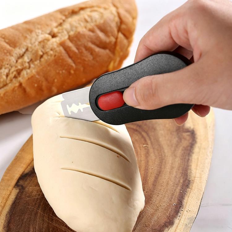 Retractable bread scoring knife with black handle and red button, slicing dough