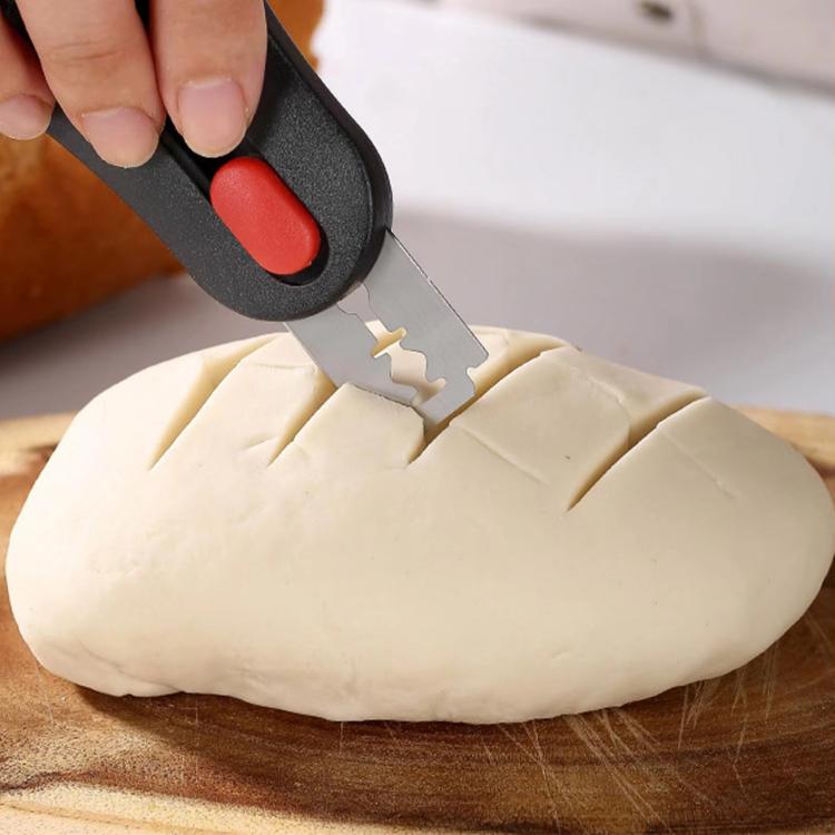 Bread scoring knife with black handle and red button, scoring folded dough
