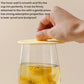 Clear cup with yellow drink and white silicone lid attached around the rim
