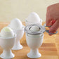 Stainless steel egg cracker tool on boiled eggs in white egg cups