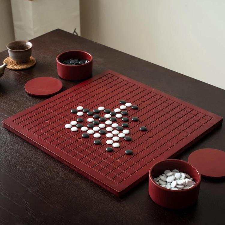 Red wooden go board with black and white stones and two matching storage jars