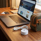 White USB charger base with cable on desk beside laptop