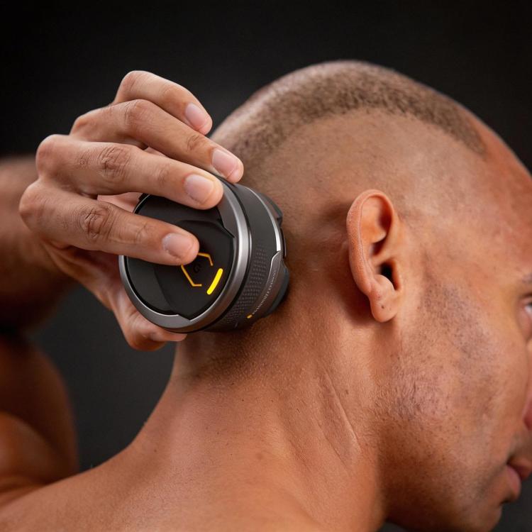 Electric shaver head held to a bald scalp, five foil cutters visible
