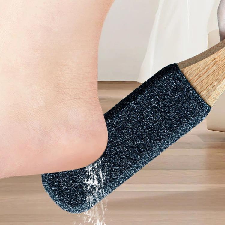 Foot callus remover with dark abrasive pad and bamboo handle, near a foot