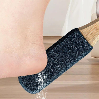 Foot callus remover with dark abrasive pad and bamboo handle, near a foot