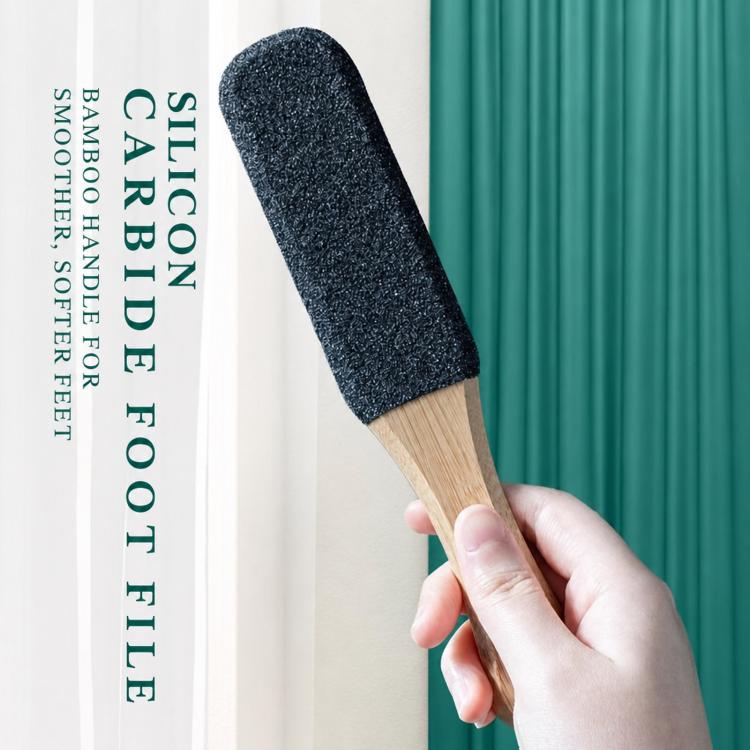 Foot callus remover held in hand, featuring dark abrasive pad on bamboo handle
