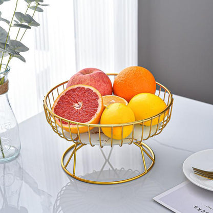 Round wrought iron fruit tray with gold stand holding oranges and grapefruit halves.