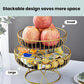 Stackable two-tier wrought iron fruit stand with gold frame holding apples and wrapped candies.