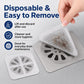 Hand lifting a disposable square white mesh drain hair catcher from a metal drain