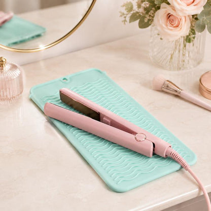 Mint teal heat-resistant silicone mat with wave texture and pink hair iron resting on it