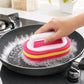 Pink, yellow, and red scrub sponge brush with handle, held over a pan