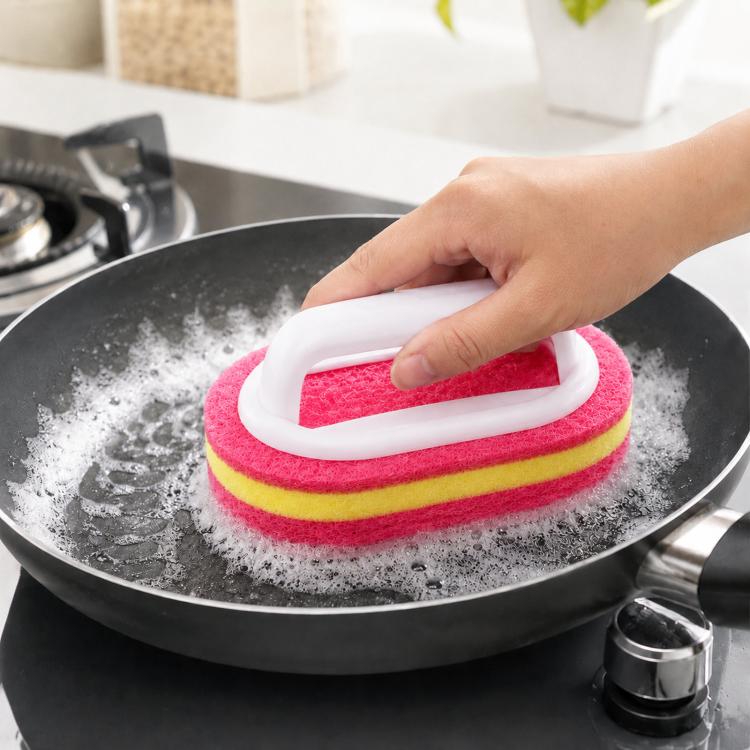 Pink, yellow, and red scrub sponge brush with handle, held over a pan
