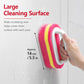Pink and yellow scrub sponge brush with blue handle, wiping a wall