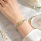 Green jade-style beaded bracelet with interlocking double loop centerpiece on wrist, close-up