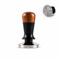 Coffee tamper with walnut wood handle, black body, and stainless flat base on a white stand