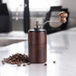 Dark wood hand-cranked coffee grinder with crank handle and metal grind assembly