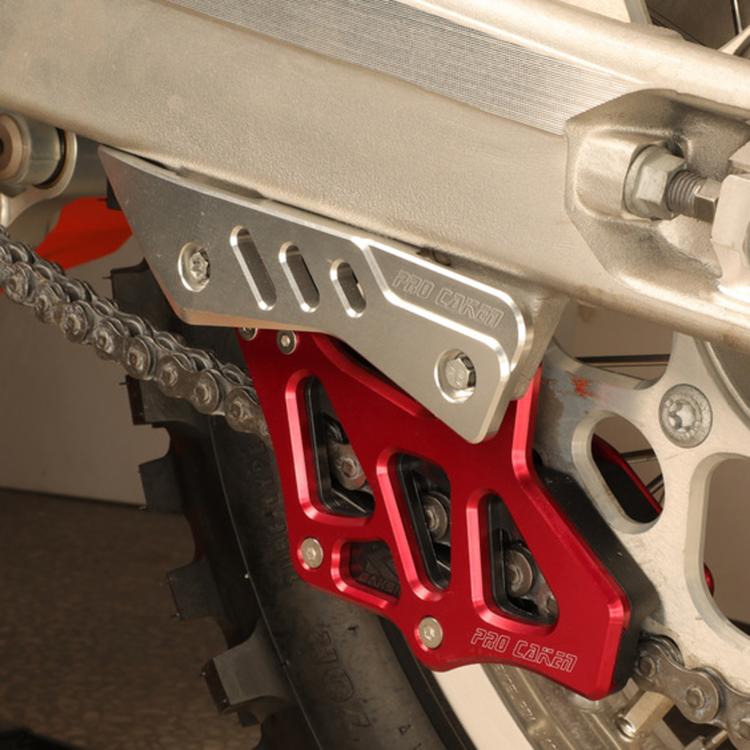 Red chain guide anti-collision guard installed on a motorcycle swingarm near the chain.