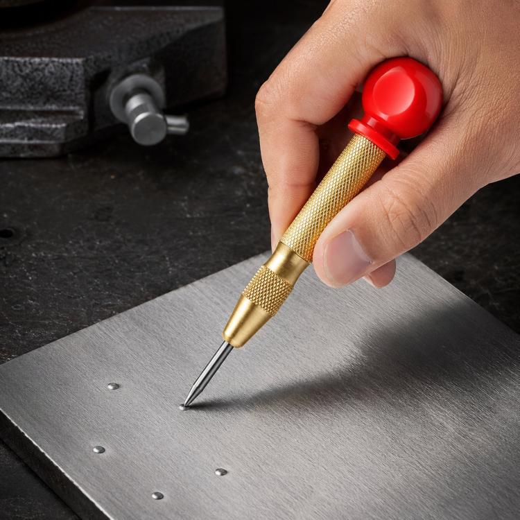 Spring-loaded center punch with red grip, gold knurled handle, and pointed tip