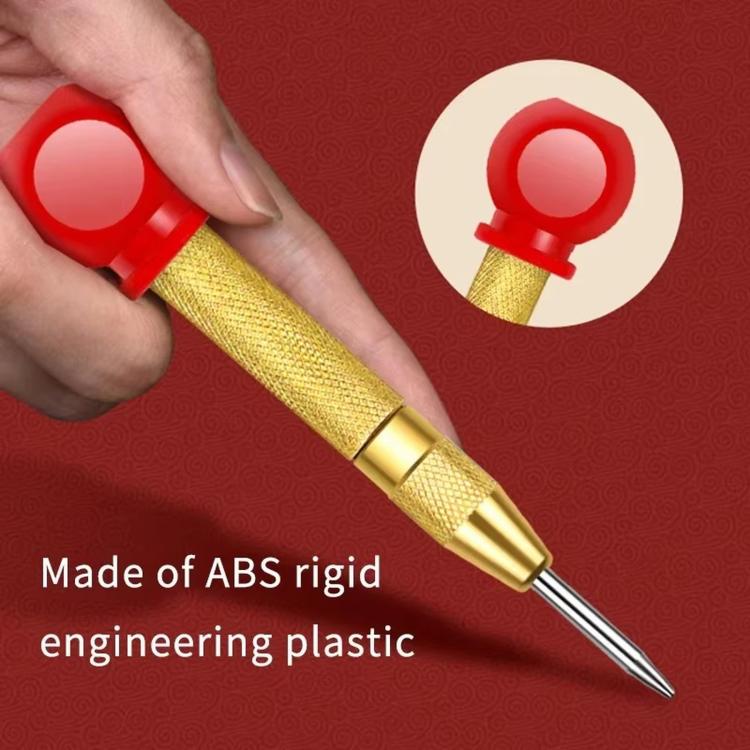 Center punch with red grip and gold body held by hand, pointed tip visible