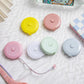Mini dual-scale tape measures with pastel round housings, retractable tape on tabletop