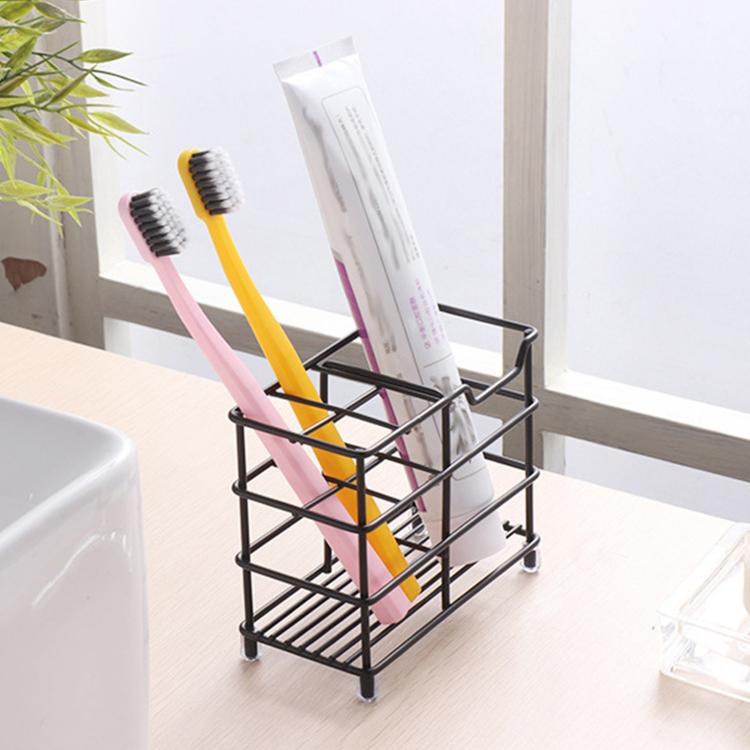 Black wrought iron toothbrush storage rack holding toothbrushes and a toothpaste tube