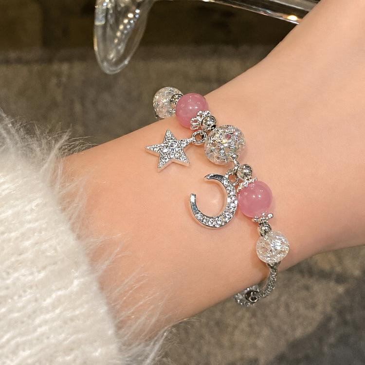 Silver-tone charm bracelet with pink beads, star and moon charms, and crystal accents