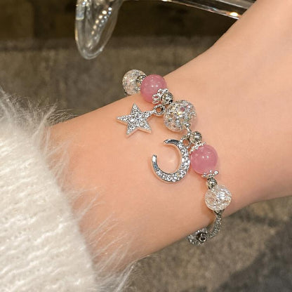 Silver-tone charm bracelet with pink beads, star and moon charms, and crystal accents