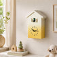 House-shaped wall clock with yellow gradient face, black hands, and bird chime window