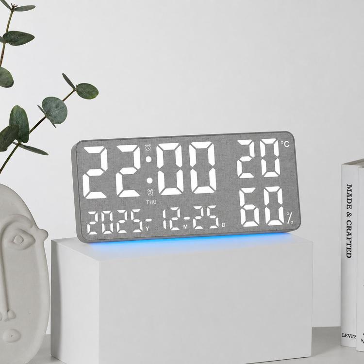 Gray fabric digital wall clock with large white LED time, temperature, and humidity display.