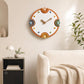 Modern wall clock with orange rim, cream dial, colorful numbers, and metal hands