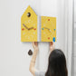 Yellow dual-face corner wall clock shown being mounted, house shape with knob and colored markers