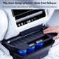 Rear seat storage box with flip cover open, holding items in molded black compartment