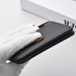 Men's black vertical wallet held in a hand, showing smooth leather-like texture