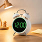 White twin-bell digital alarm clock with green glowing ring and green LED time display