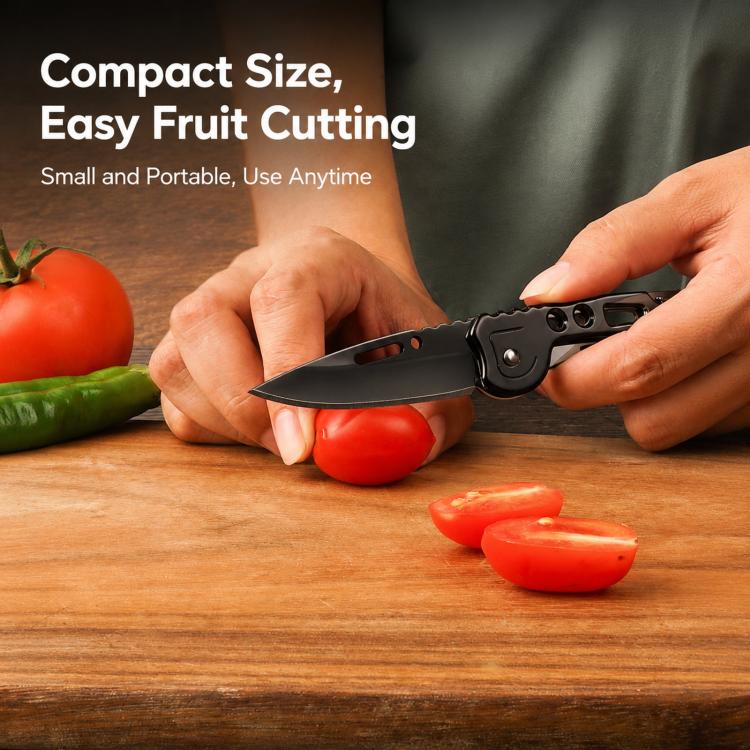 Black folding fruit knife slicing tomato, used on a cutting surface