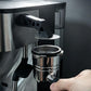 Espresso puck screen holder stand with black extraction tool, next to metal portafilter