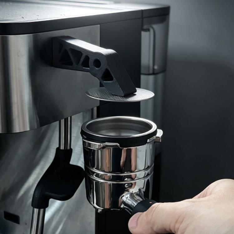 Espresso puck screen holder stand with black extraction tool, next to metal portafilter