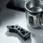 Espresso puck screen holder stand with black extraction tool beside metal basket