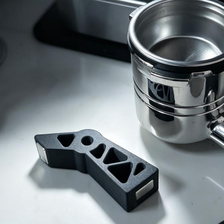 Espresso puck screen holder stand with black extraction tool beside metal basket