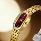 Close-up of gold oval quartz dress watch with maroon dial and gold crown