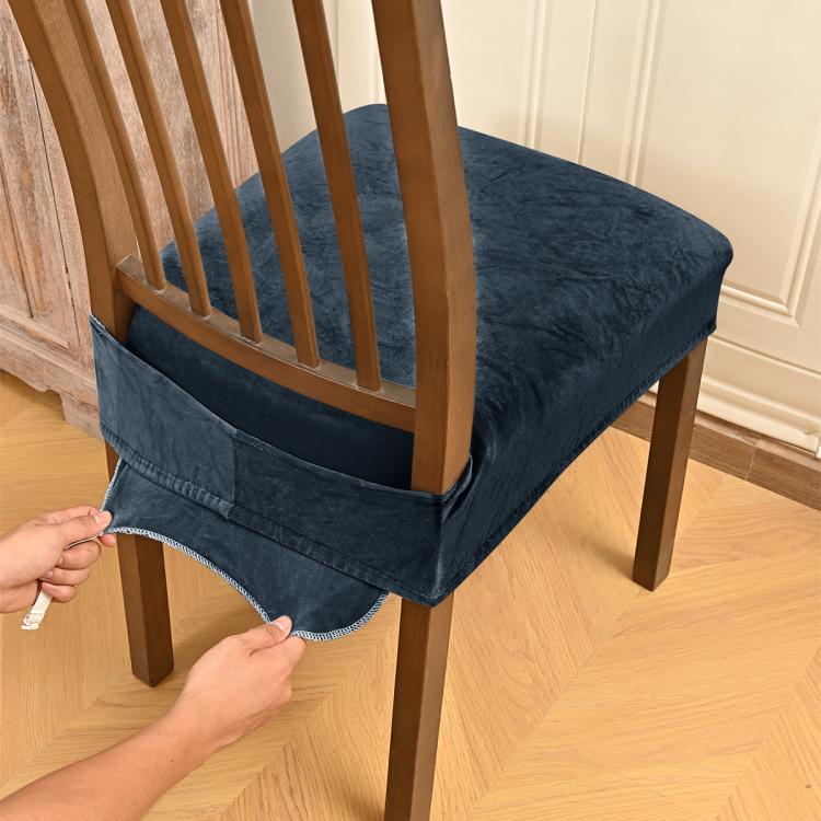 Dark blue-gray velvet stretch chair seat cover with buckle straps, being fitted on chair