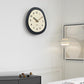 Modern oval wall clock with dark outer ring and cream dial showing numbered hours