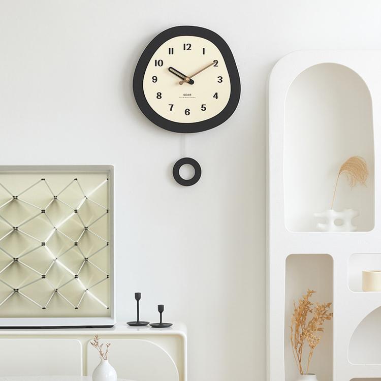 Modern oval wall clock on wall with dark bezel and cream face with black numbers