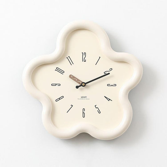 Flower-shaped wall clock with cream frame, beige face, black hands and Arabic numerals.