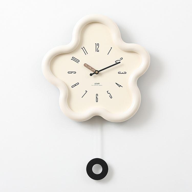 Flower-shaped wall clock with cream frame, cream face, black hands; hanging cord visible.