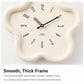 Cream flower-shaped wall clock with black hands and minimal numeric markers
