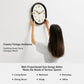 Person hanging a retro oval wall clock with black frame and cream dial.