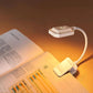 White clip-on LED reading lamp shining over pages with flexible curved neck