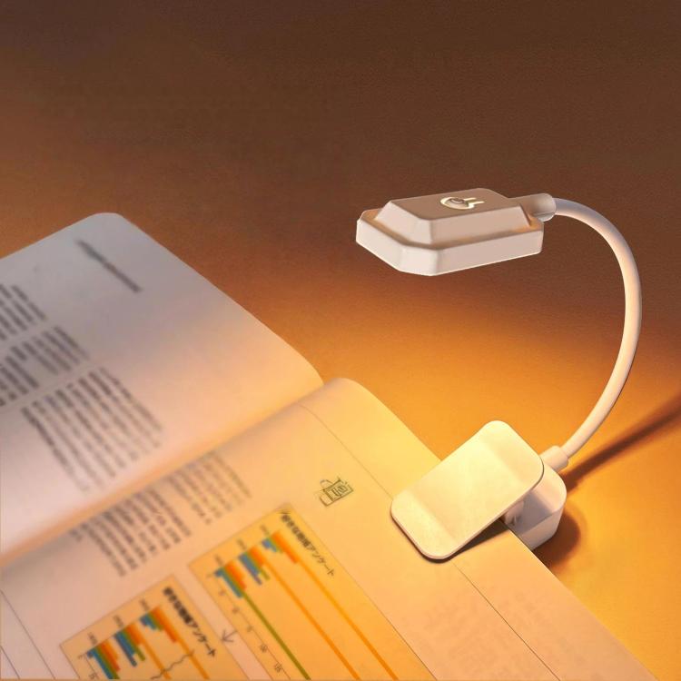 White clip-on LED reading lamp shining over pages with flexible curved neck