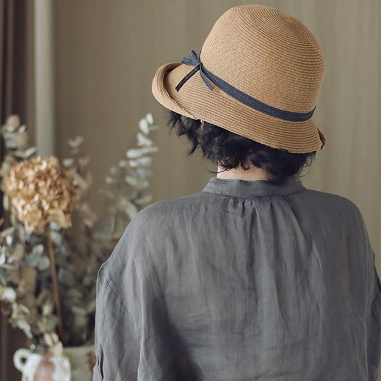Straw cloche sun hat with blue band and ribbon bow, woman seen from the back